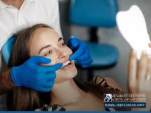 Patient examining new smile with dental implants at Advanced Dentistry & Dental Implant Center