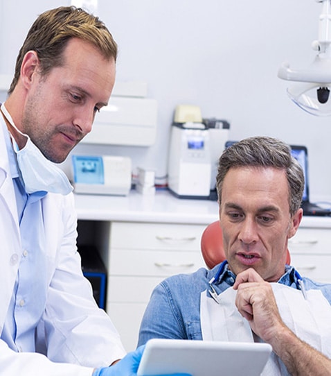 dentist-discussing-over-digital-tablet-with-male You Might Need Teeth Whitening To Reverse The Effects Of Aging
